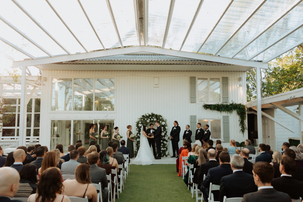 Full wedding ceremony at The Juliana wedding venue with white and green floral arch by Lily and Olive, luxury floral arrangements. 